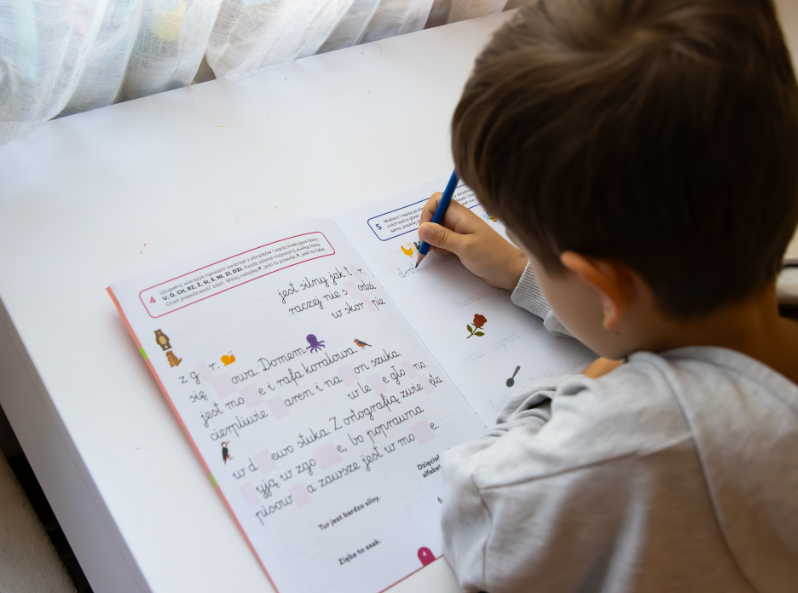 Chłopiec pisze dyktando w książeczce EDUseria. Dyktanda. Ćwiczenia